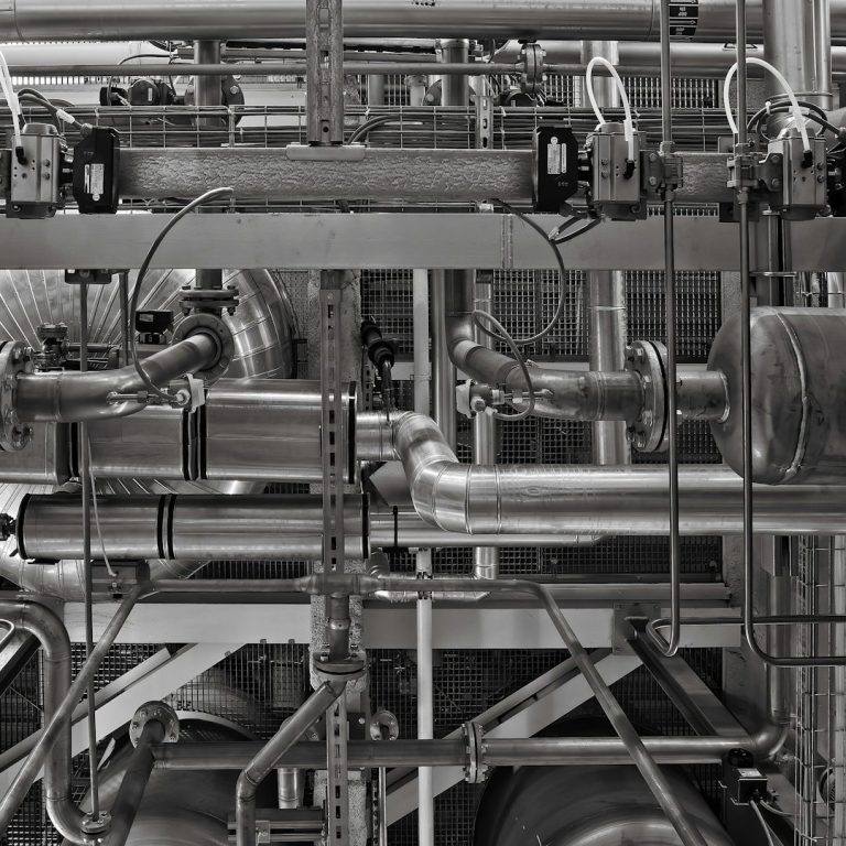 Foto von Ricardo Gomez Angel von Unsplash Verzahntes Rohrleitungssystem aus Metall mit Ventilen und Sensoren.